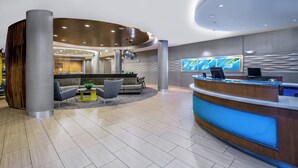 A modern reception area with a curved desk, seating, and a large abstract painting on the wall. - SpringHill Suites by Marriott San Antonio SeaWorld Lackland (San Antonio)