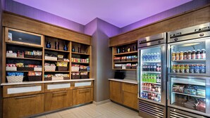 A well-stocked snack and beverage refrigerator area in a hotel lobby, with various snacks and drinks visible. - SpringHill Suites by Marriott San Antonio SeaWorld Lackland (San Antonio)
