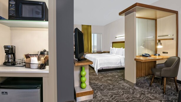 A hotel room with a bed, desk, chair, TV, microwave, coffee maker, and a small refrigerator. - SpringHill Suites by Marriott San Antonio SeaWorld Lackland (San Antonio)