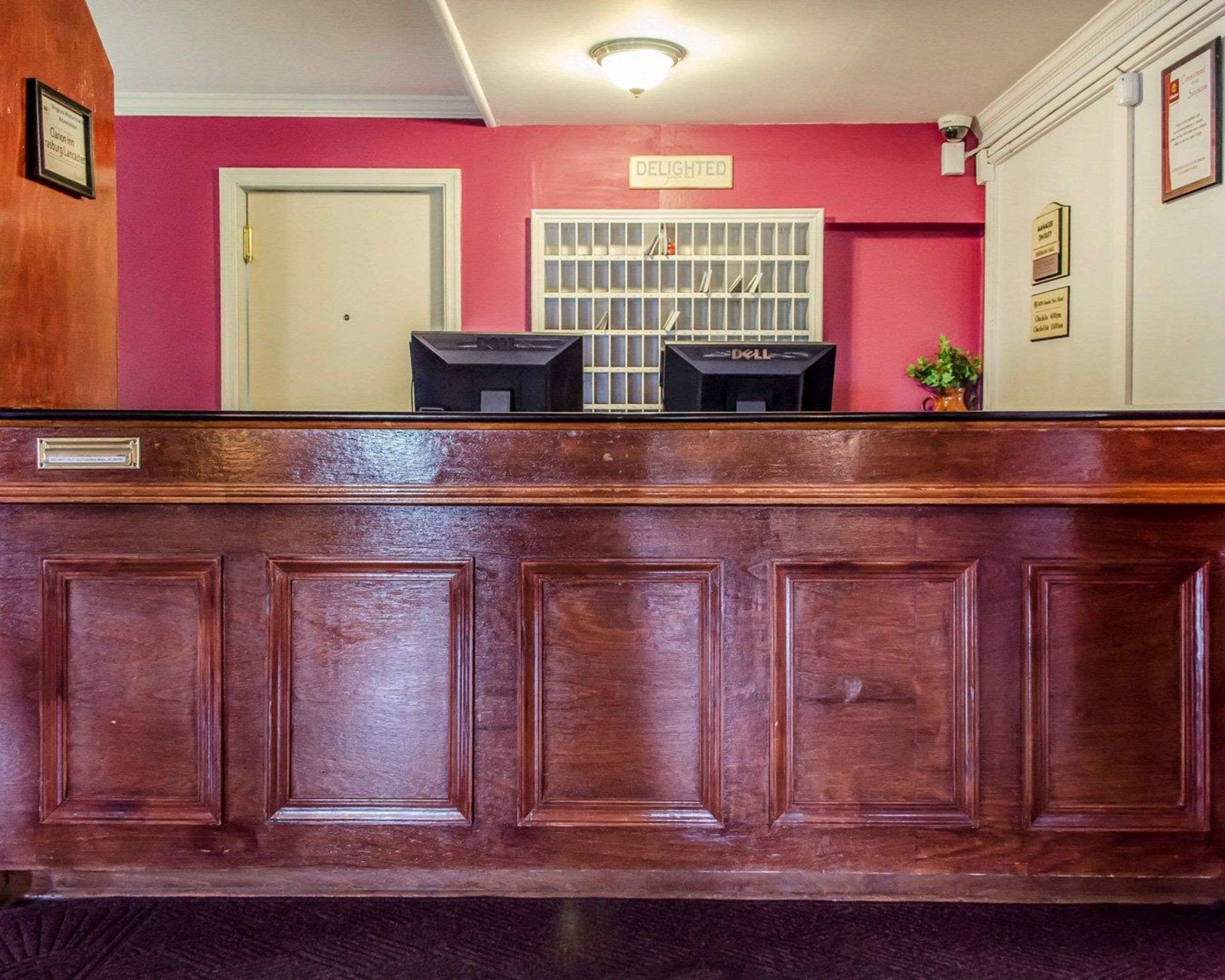 Un mostrador de recepción con acabado de madera, una puerta cerrada y una ventana con diseño de cuadrícula.