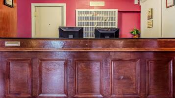 Un mostrador de recepción con acabado de madera, una puerta cerrada y una ventana con diseño de cuadrícula.