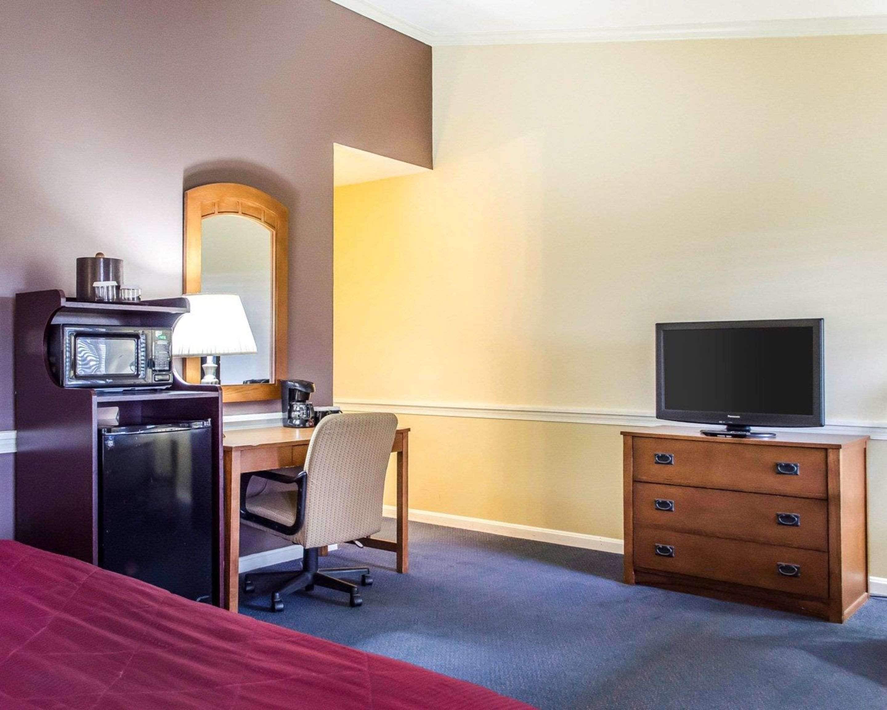 A hotel room with a bed, a desk with a computer, a television, a microwave, and a coffee maker.