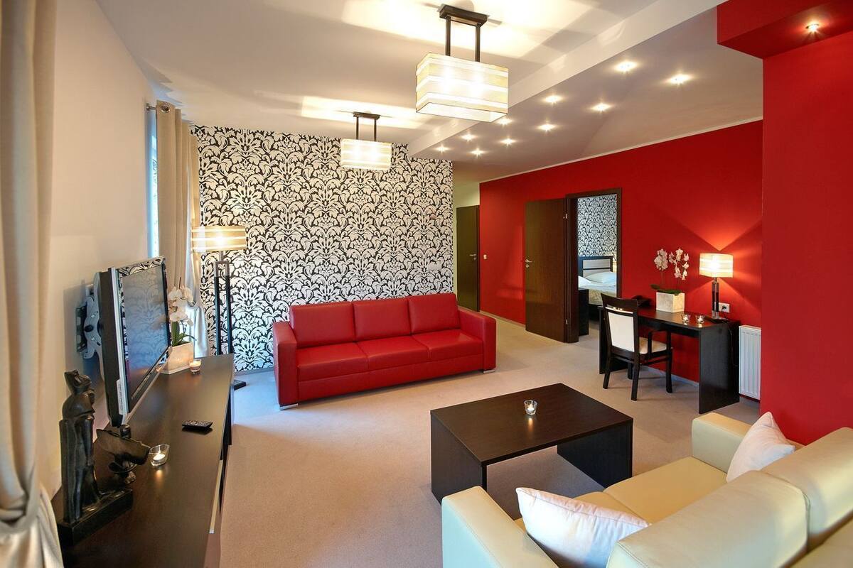 A modern living room with a red sofa, a white sofa, a black coffee table, and a dining area with a table and chairs.