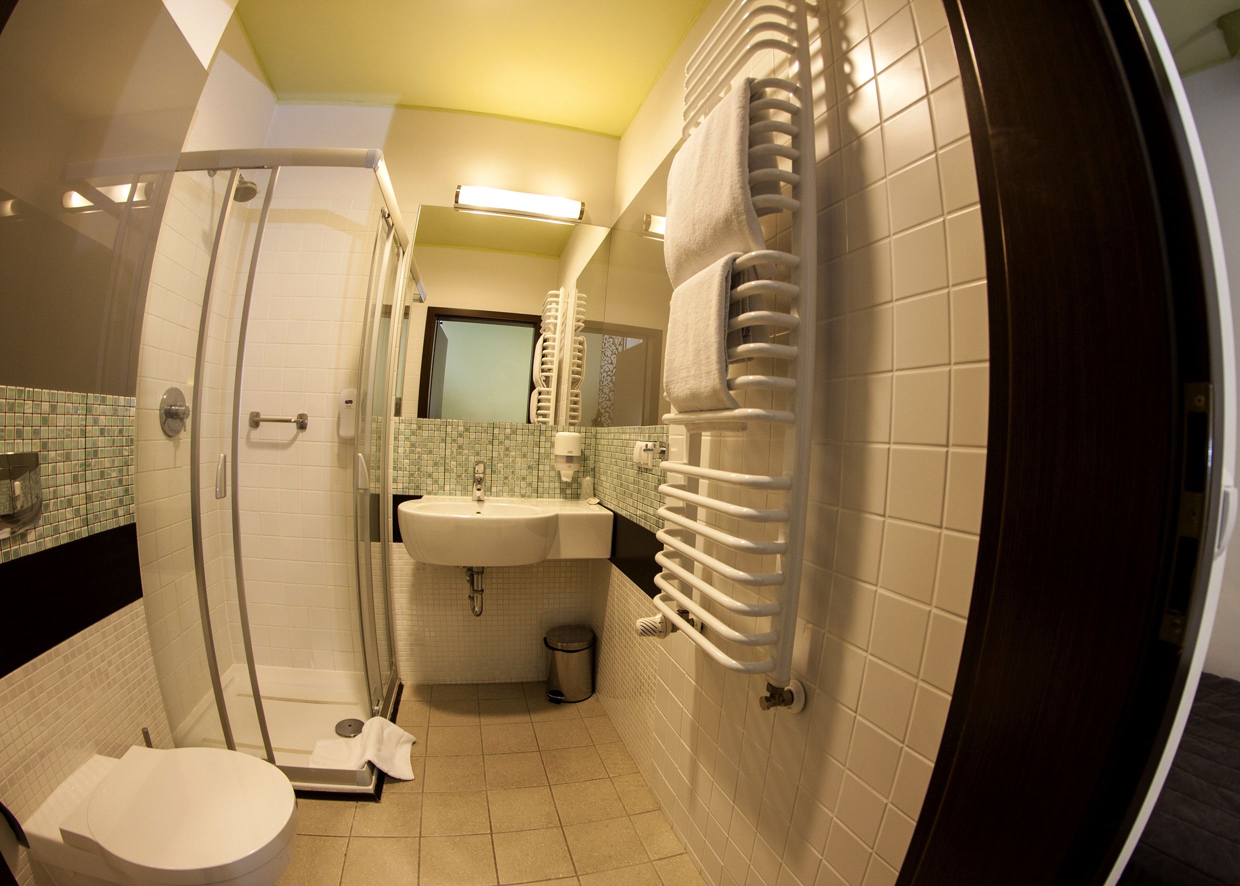 A bathroom with a shower, toilet, sink, and towel rack.