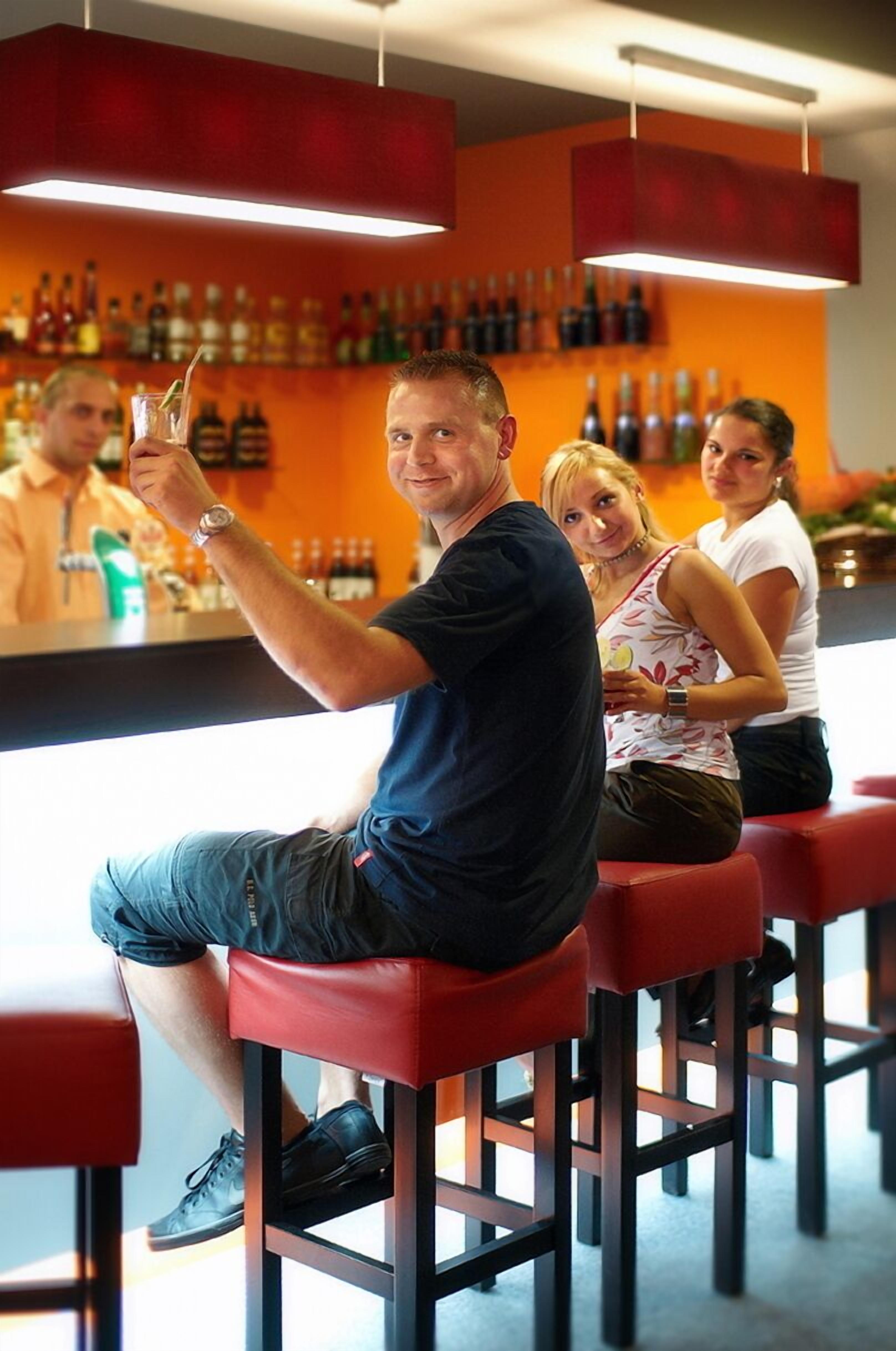 A bar area with red stools and a wall of bottles.