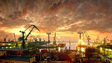 A port with cranes and industrial buildings, likely a shipyard or dock area.