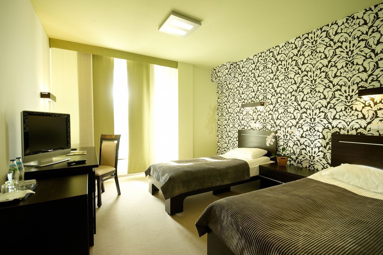 A hotel room with two beds, a desk with a laptop, a television, and a chair.