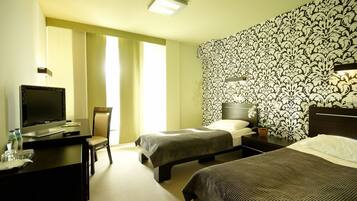 A hotel room with two beds, a desk with a laptop, a television, and a chair.