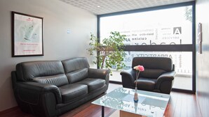 A modern interior with two black leather sofas, a glass coffee table, and a framed map on the wall. - Appart'City Classic Nîmes Centre (Nîmes)