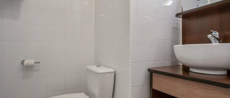 A modern bathroom with a white toilet, a sink, and a mirror above the mirror cabinet.