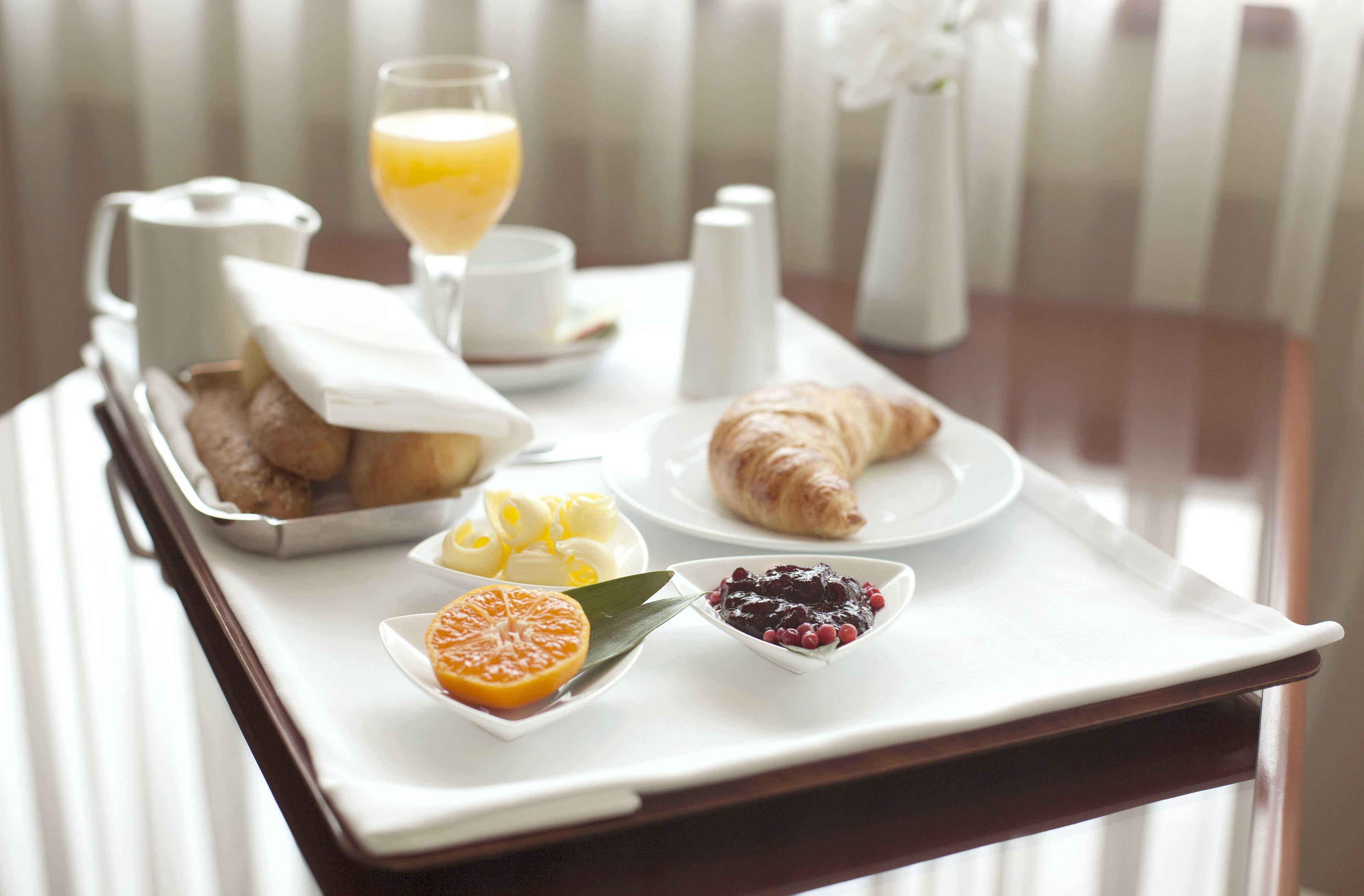 A breakfast tray with croissants, orange slices, and berries on a table.