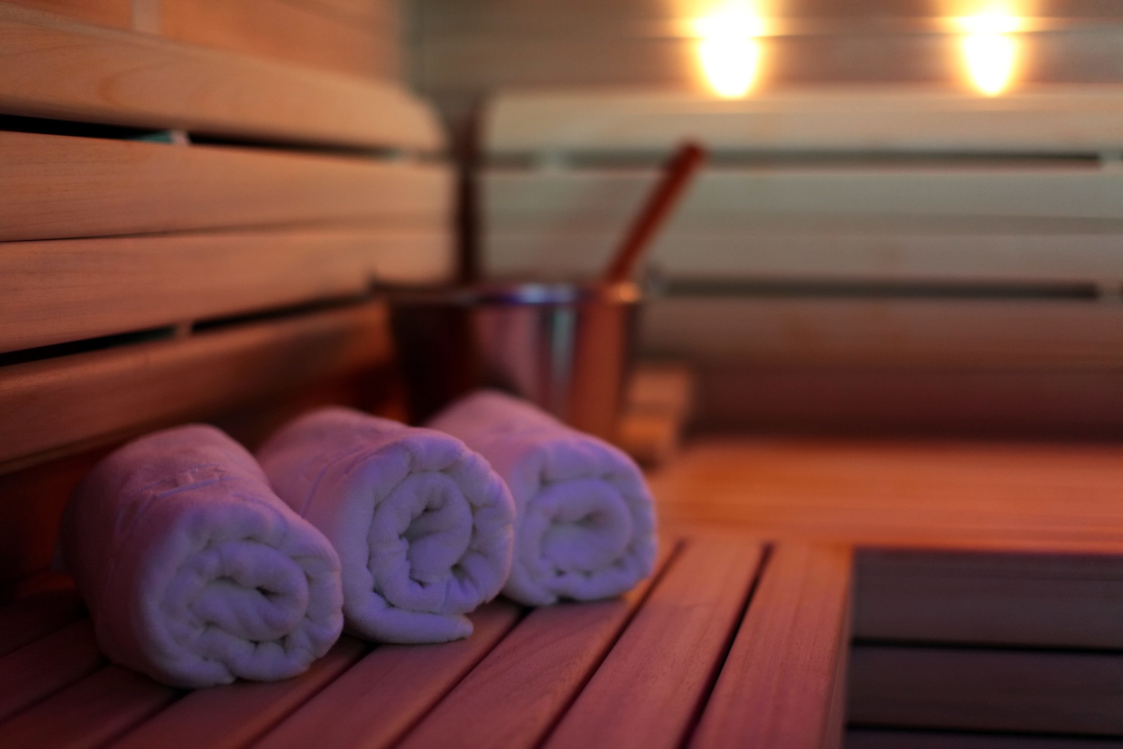 A wooden bench with rolled towels and a metal container with a spoon.