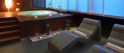 A modern spa area with a hot tub, lounge chairs, and a wooden reception desk.