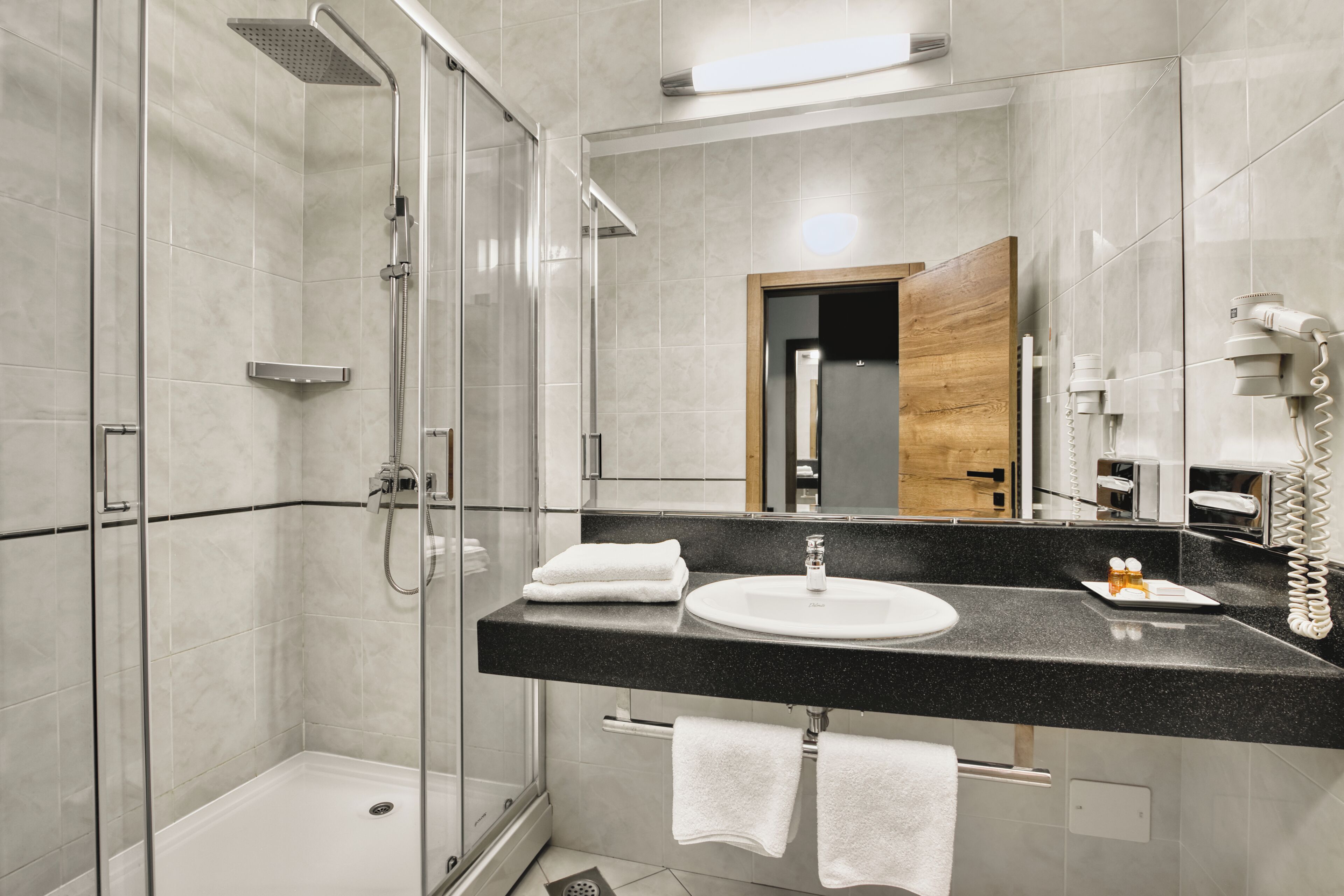 A modern bathroom with a glass-enclosed shower, a black countertop sink, and a mirror.