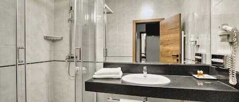 A modern bathroom with a glass-enclosed shower, a black countertop sink, and a mirror.