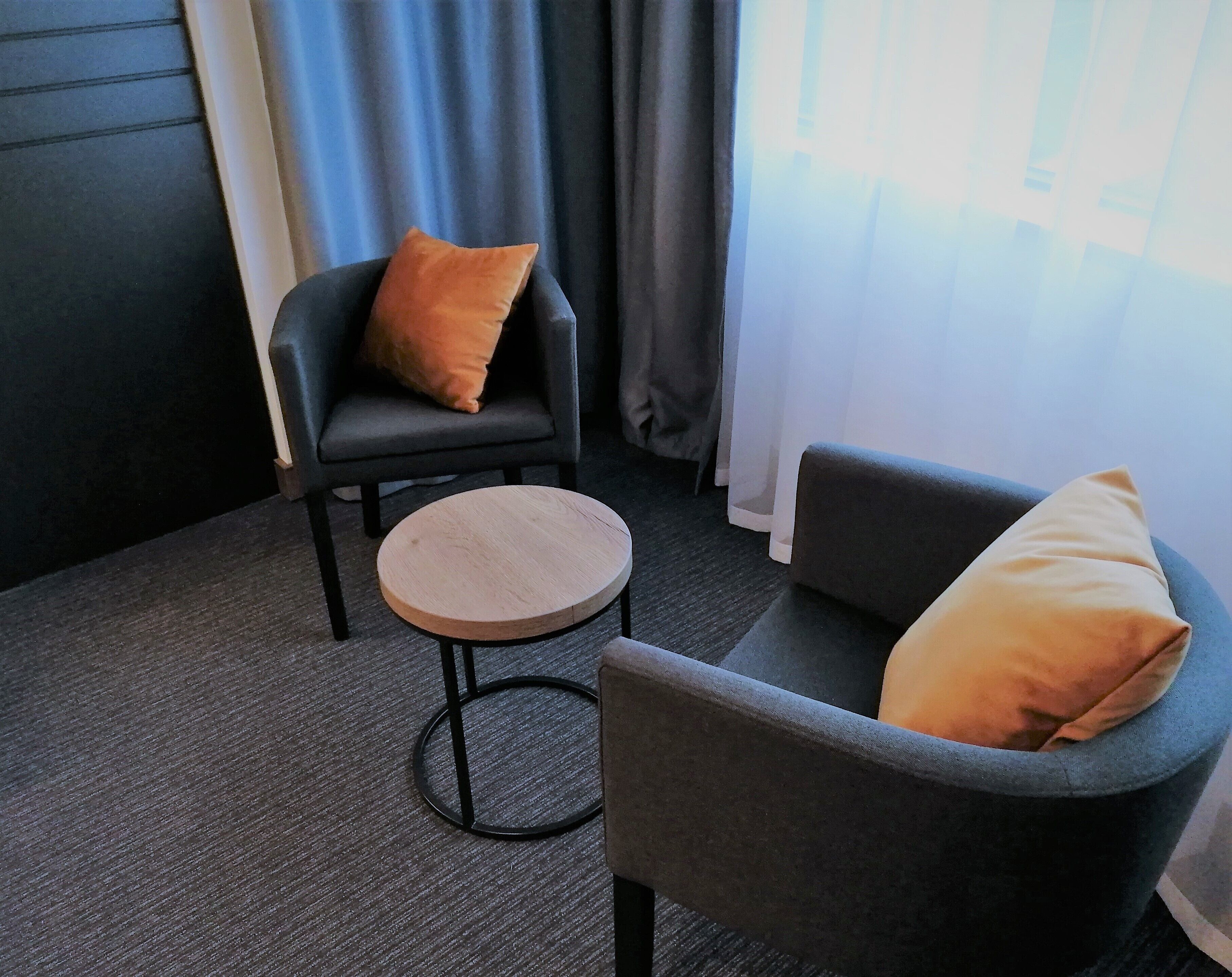 A room with a dark grey armchair and a smaller round table, both with matching cushions.