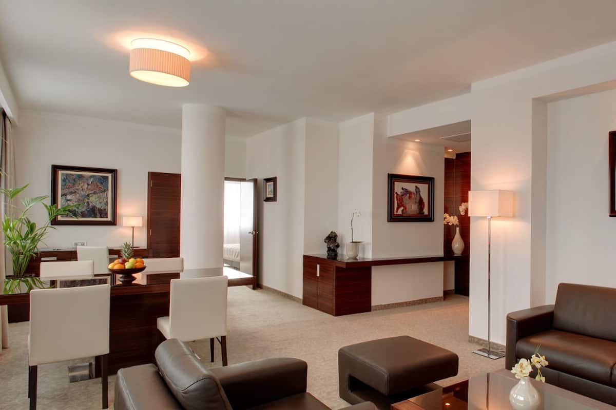 A modern hotel lobby with a dining area, a reception desk, a sofa, and a large painting on the wall.