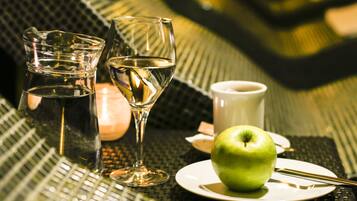 Una mesa con una manzana verde, un vaso de agua, una copa de vino y una taza.