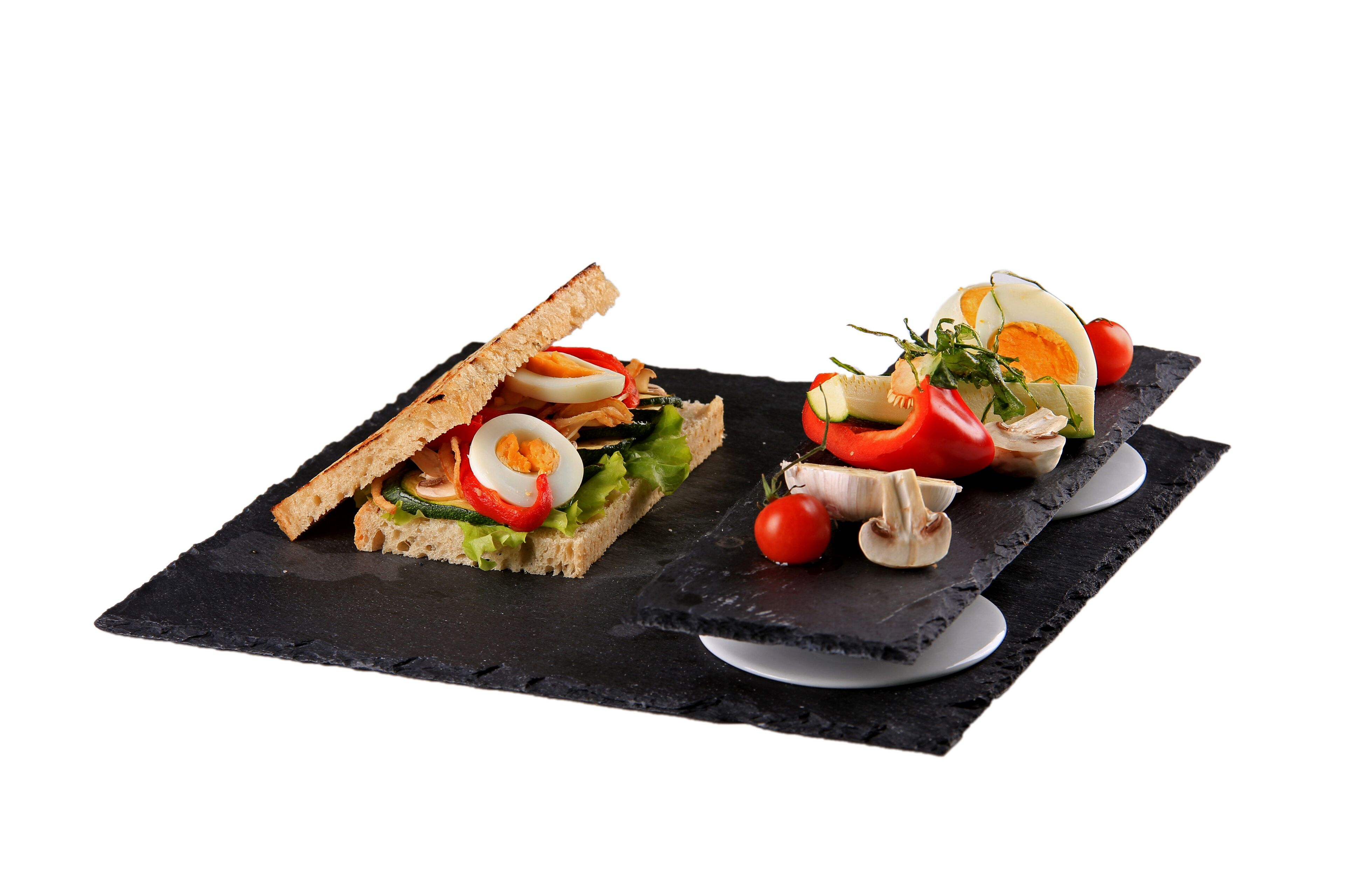 Two sandwiches on a black slate board.