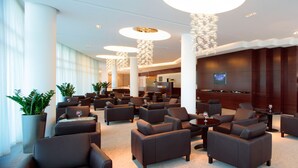 A modern hotel lobby with leather sofas, a bar area, and large decorative light fixtures. - Hotel Aristos (Zagreb)