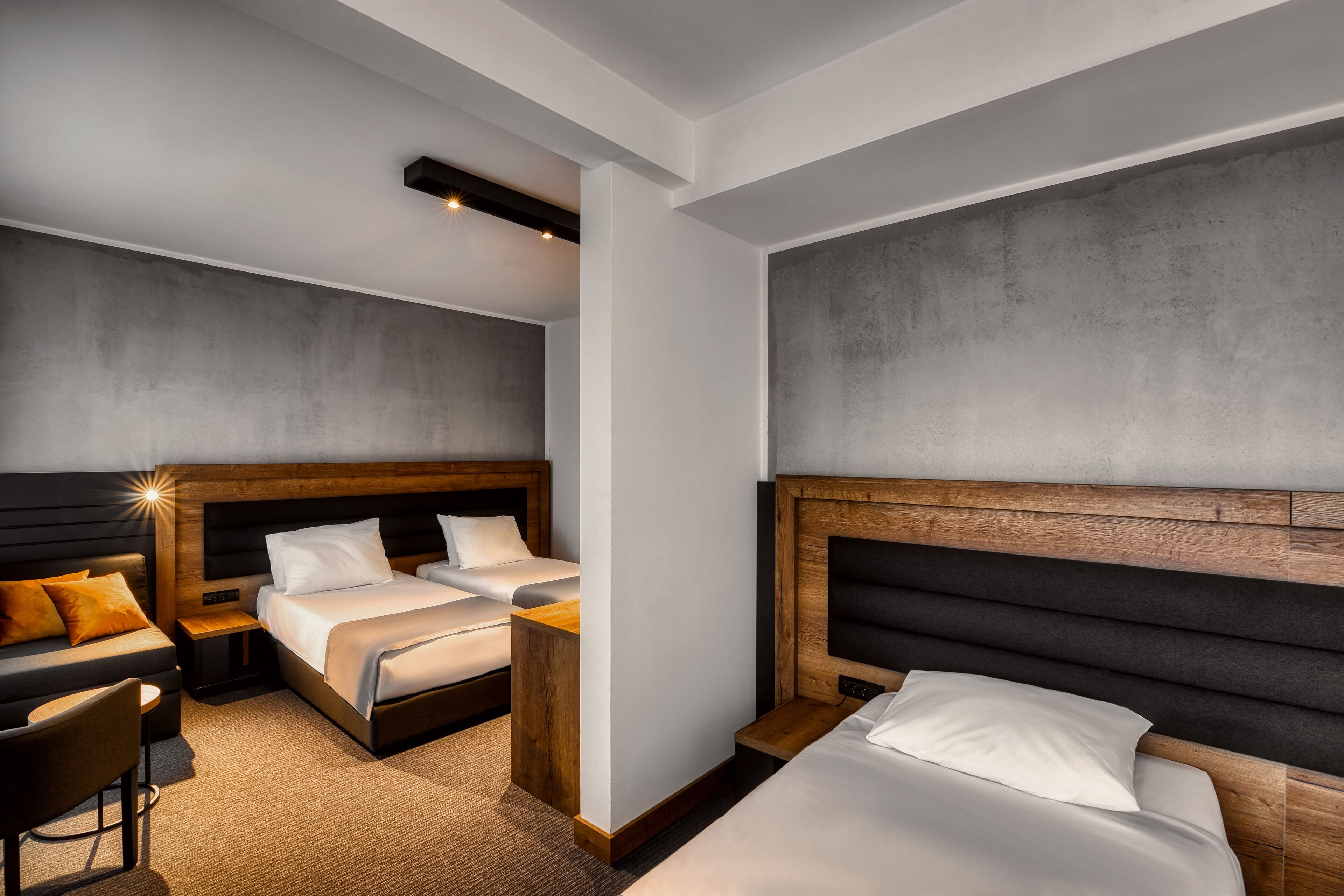 Una habitación de hotel moderna con dos camas, un sofá, una mesita y una silla.
