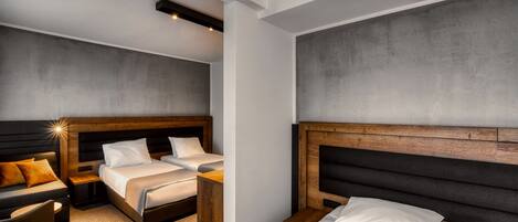 Una habitación de hotel moderna con dos camas, un sofá, una mesita y una silla.