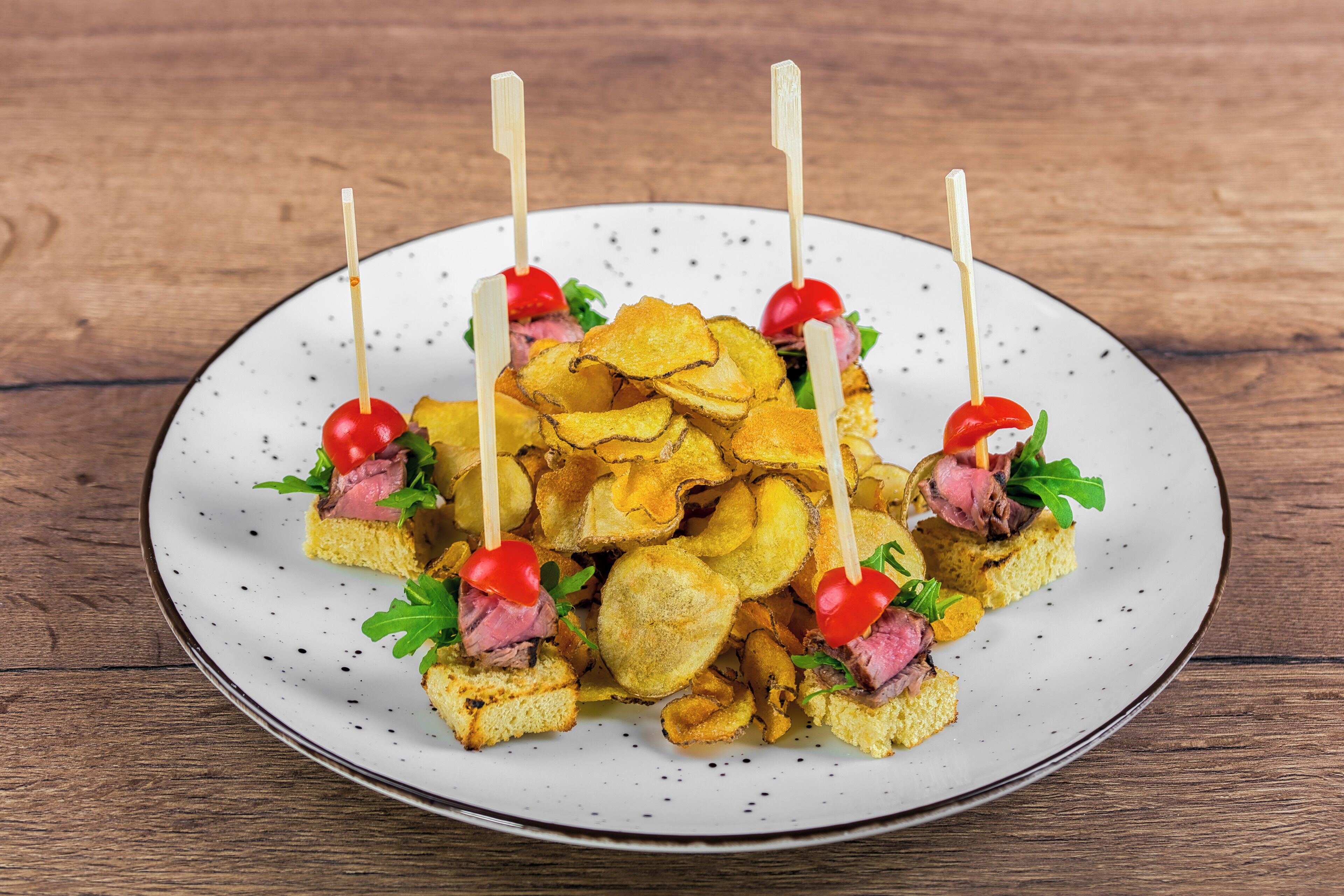 Ein Teller Essen mit Spießen, Chips und Garnituren.