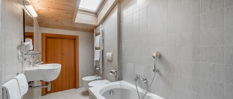 Un bany modern amb un fanal, una banyera, un lavabo i un vàter.
