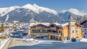 Un hotel con un telesilla, montañas nevadas y un cielo despejado.
