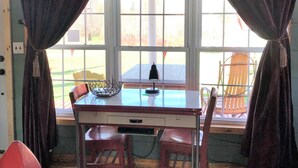 Una habitación con paredes de madera, una mesa con sillas, un televisor sobre la mesa y una ventana con cortinas.