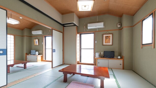 Een traditionele Japanse kamer met tatami vloerbedekking, een lage tafel, een kussen en een televisie op een lage standaard.