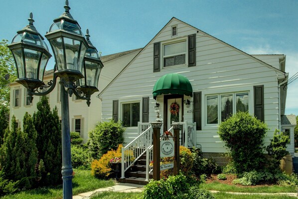A two-story house with a green awning, a front porch, and a sign indicating it is a bed and breakfast.