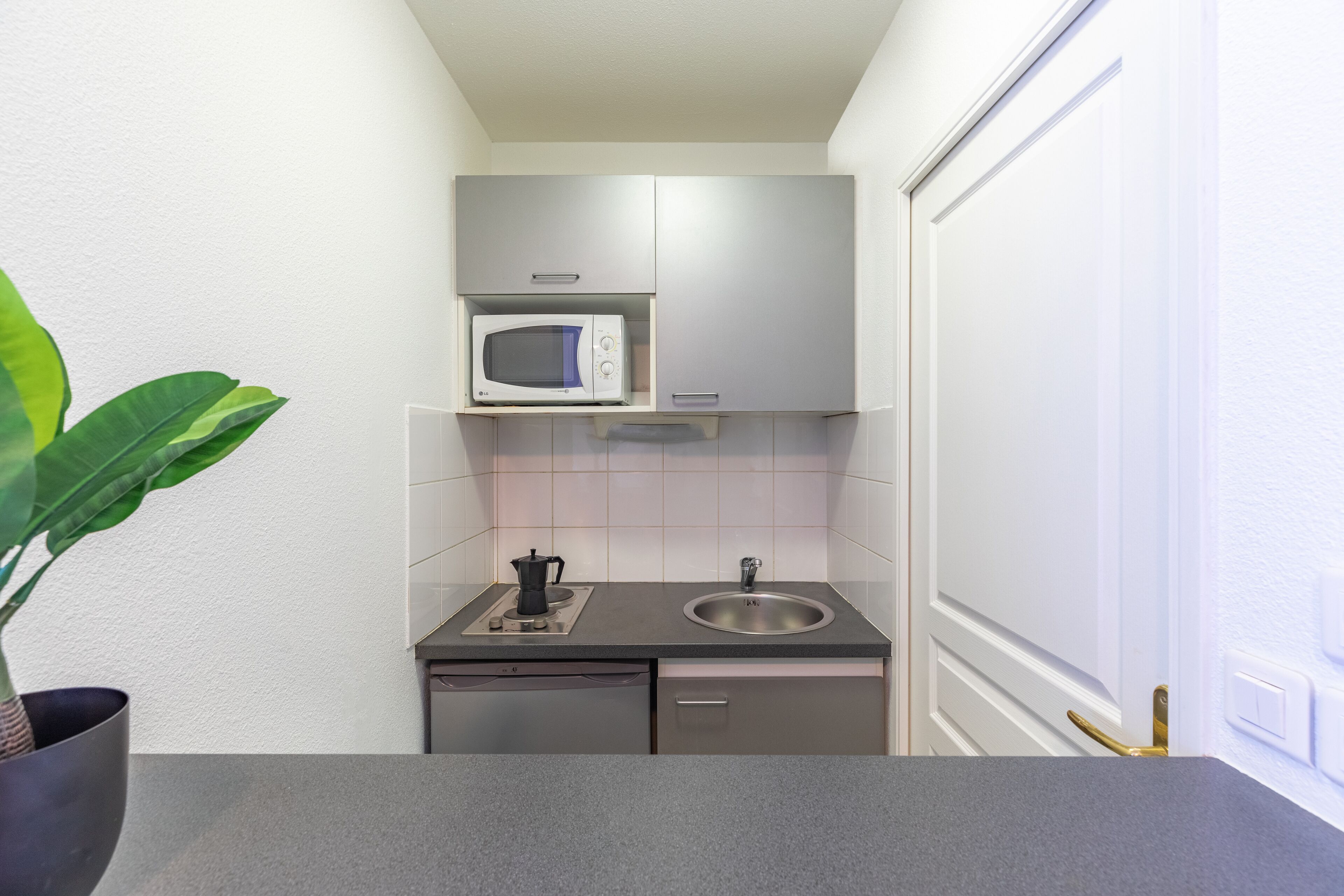 Cocina compacta con microondas, lavabo y lavavajillas pequeño.