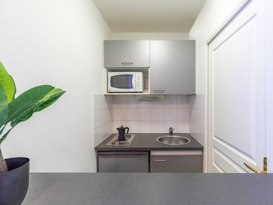 Cocina compacta con microondas, lavabo y lavavajillas pequeño.