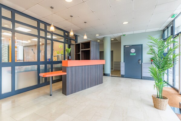A reception area with a counter, seating, and potted plants.