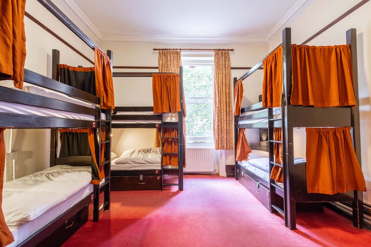 A room with bunk beds, a window with curtains, and a radiator.
