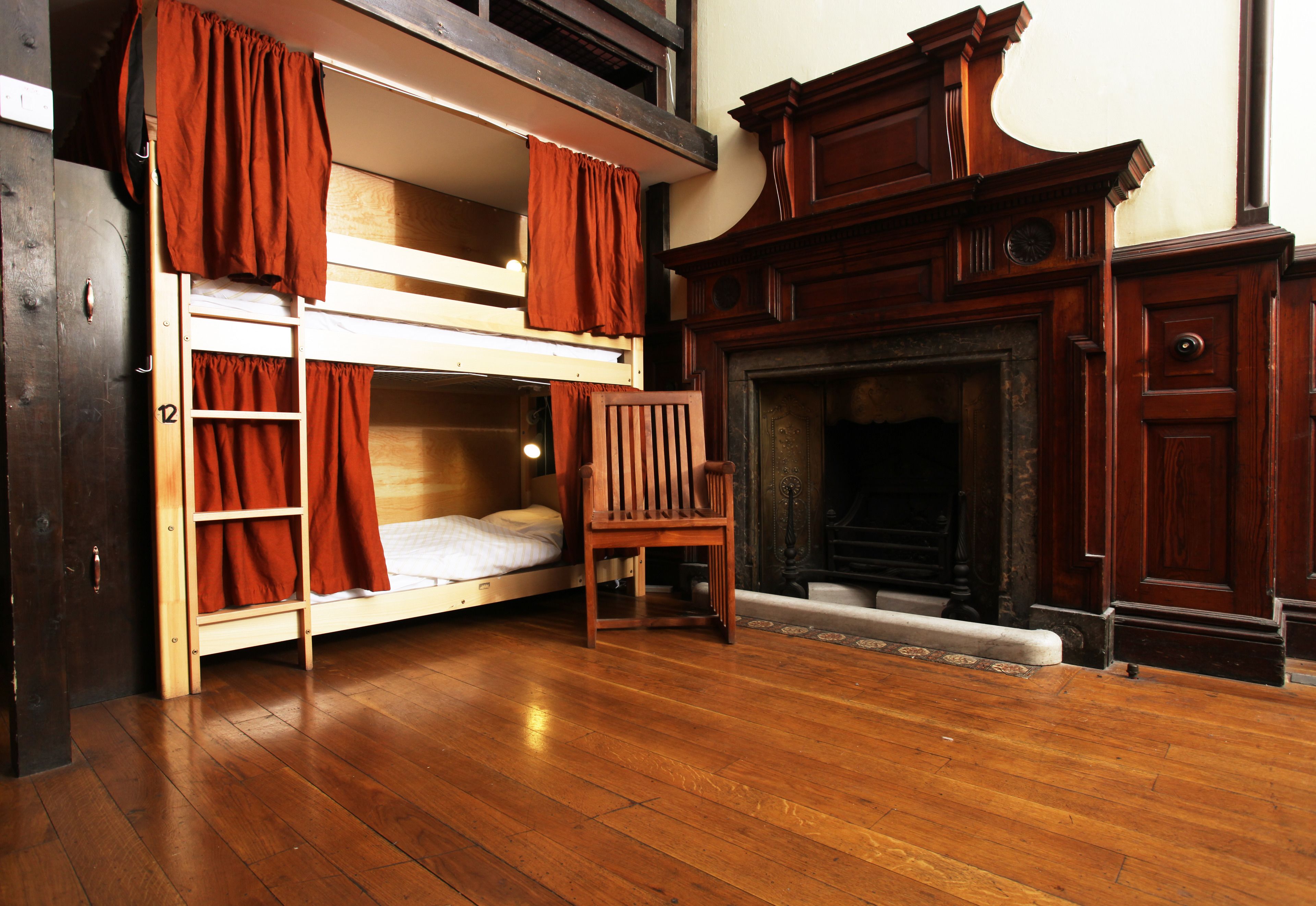 Une pièce avec un lit superposé, une chaise en bois et une cheminée.