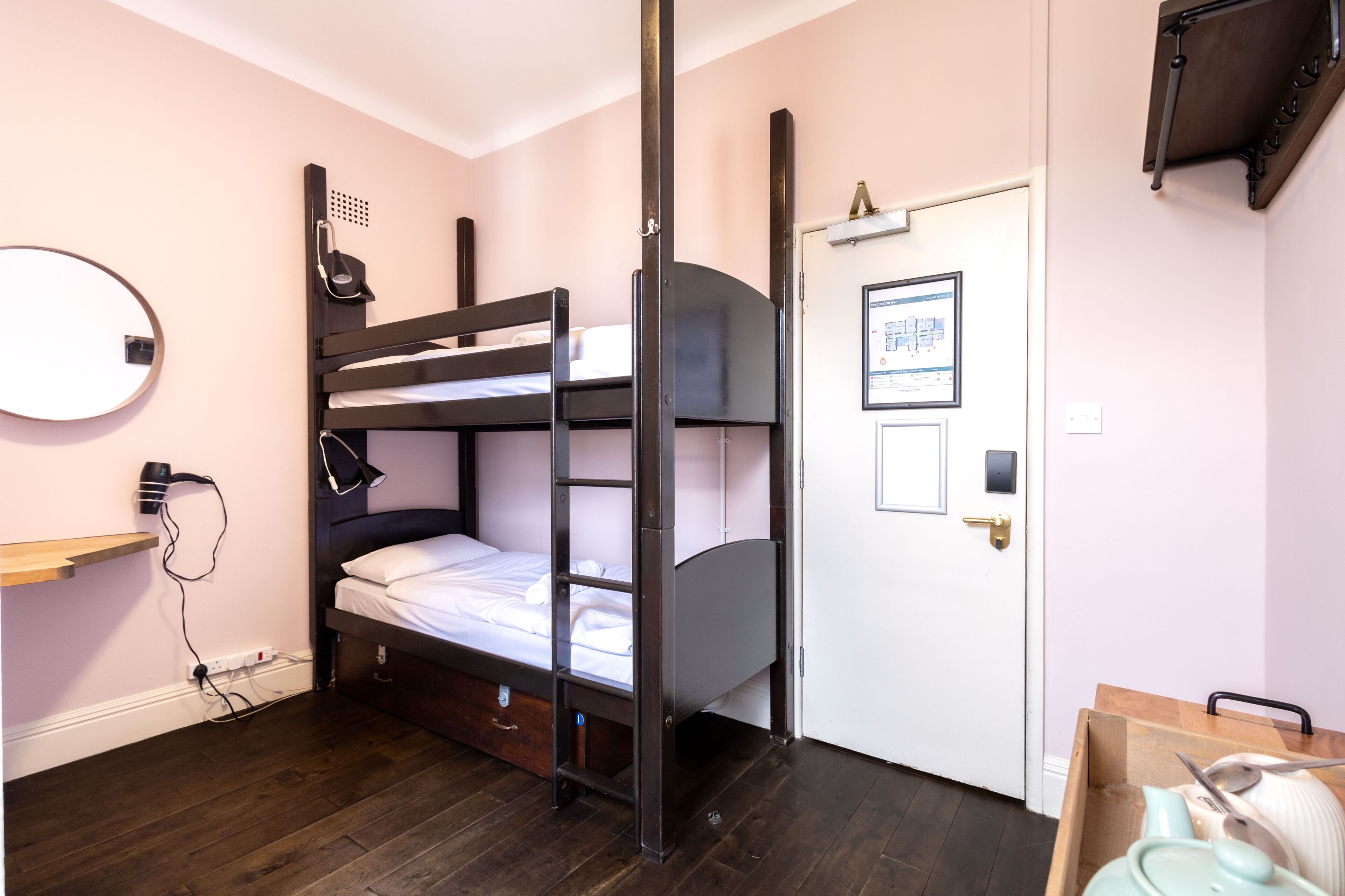 A bunk bed room with a desk, a mirror, and a door with a poster.