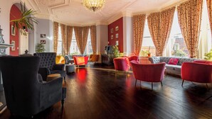 Una habitación amplia con piso de madera oscura, un candelabro y un conjunto de sofás.