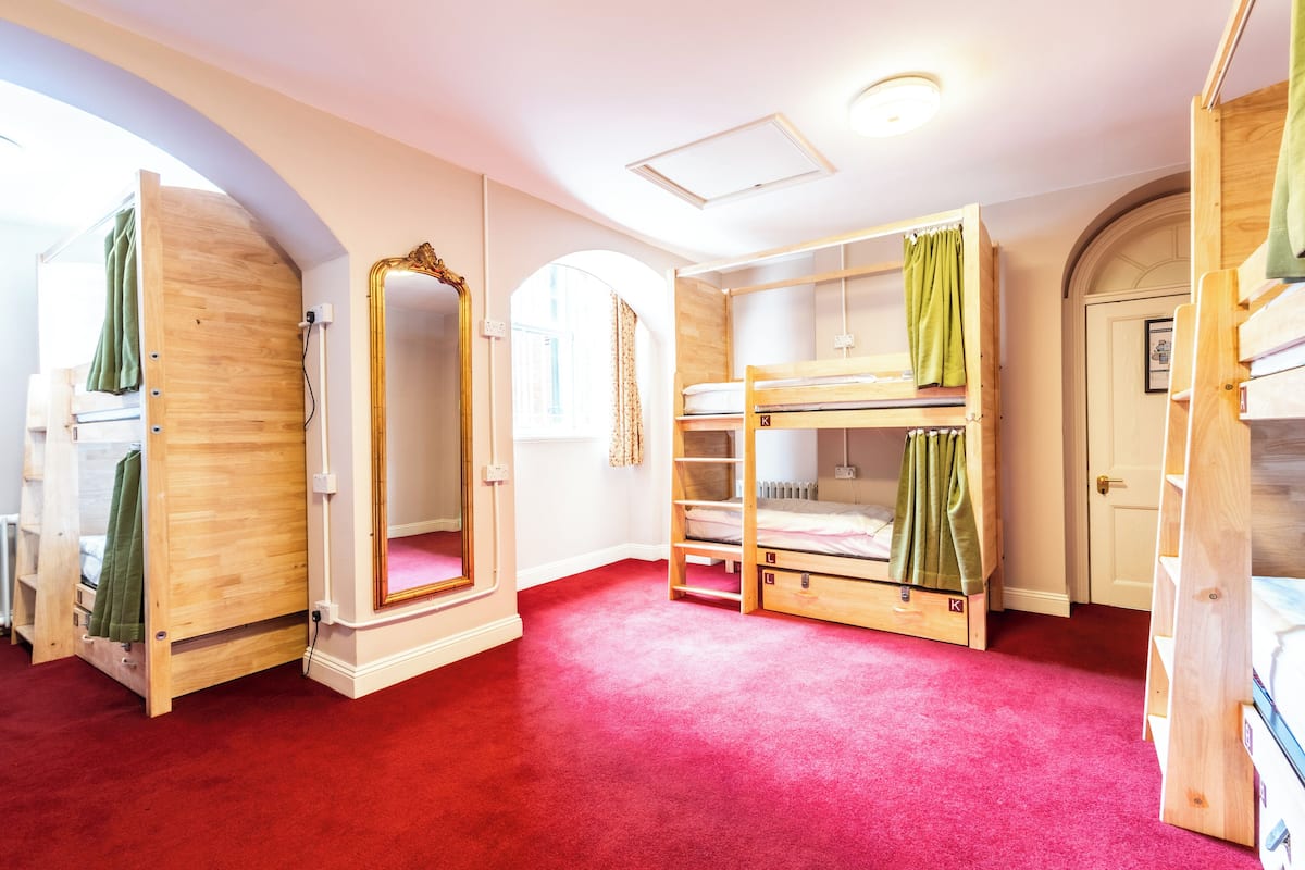 A room with bunk beds, a mirror, and a red carpet.