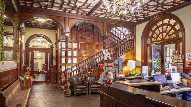 Zona de bar con decoración de madera, una escalera y una recepción con computadoras.