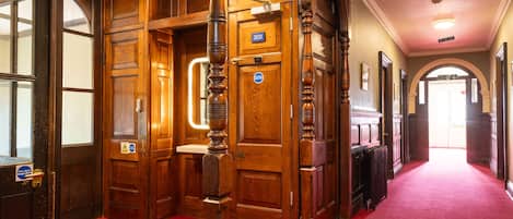 A hallway with wooden doors and a red carpet.