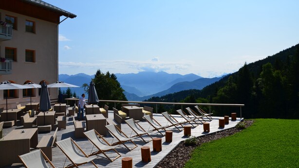 A terrace with lounge chairs and umbrellas, overlooking a mountainous landscape. - Hotel Norge (Trento)