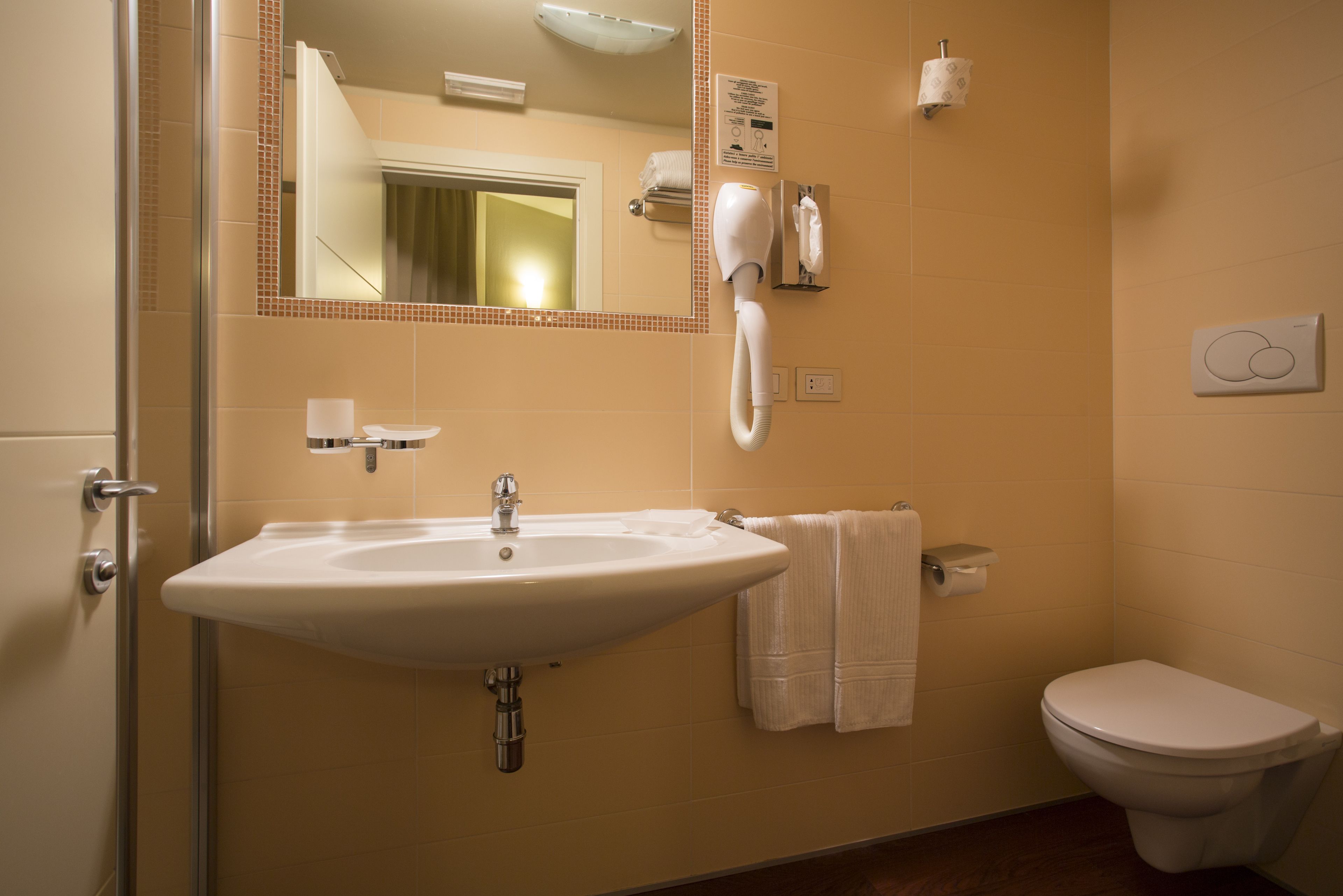 A bathroom with a sink, mirror, towel rack, toilet, and a hairdryer.