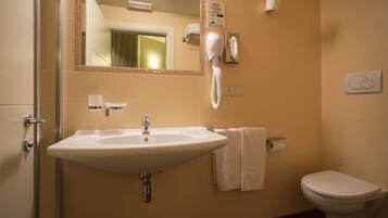 A bathroom with a sink, mirror, towel rack, toilet, and a hairdryer.