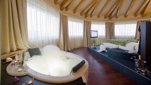 A spacious room with a large bathtub, a bed with a green bedspread, and a television on a stand. - Hotel Norge (Trento)