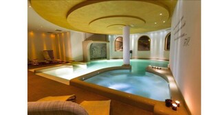 A spa area with a hot tub, seating, and a decorative ceiling. - Hotel Norge (Trento)