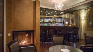 A bar area with a fireplace, seating, and a well-stocked bar. - Hotel Norge (Trento)