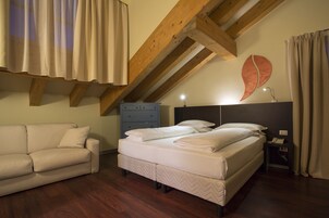 Un dormitorio con cama, mesita de noche, cómoda, sofá y vigas de madera en el techo.