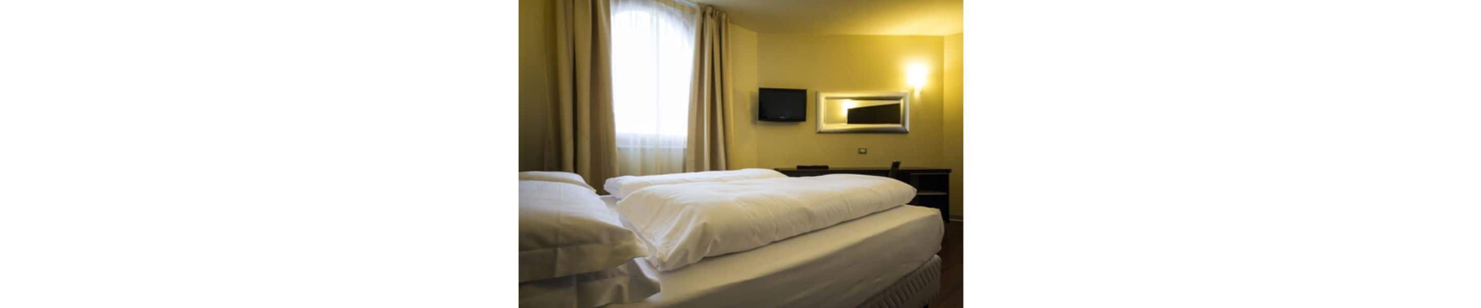 Ein Hotelzimmer mit zwei Betten, einem Fernseher und einem Spiegel an der Wand.